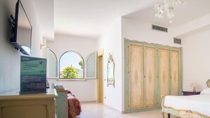 A hotel room with a bed, a desk, a chair, a wardrobe, and a window with a view of greenery. - Hotiday San Felice Circeo (San Felice Circeo)