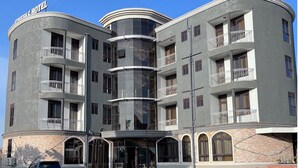 Um hotel com vários andares, fachada curva, varandas e entrada central.