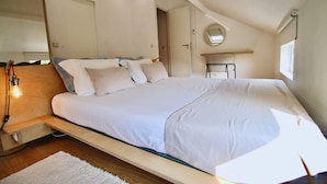Un dormitorio moderno con una cama grande, una mesita de noche, un espejo y una ventana.