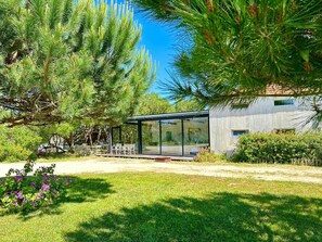 A modern house with a glass conservatory, surrounded by lush greenery and a well-maintained lawn. - Desertas Beach and Sport (Ilhavo)