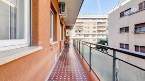 Ein schmaler Balkon mit Fliesenboden, Klimaanlagen und Blick auf angrenzende Gebäude.