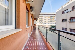 Ein schmaler Balkon mit Fliesenboden, Klimaanlagen und Blick auf angrenzende Gebäude.