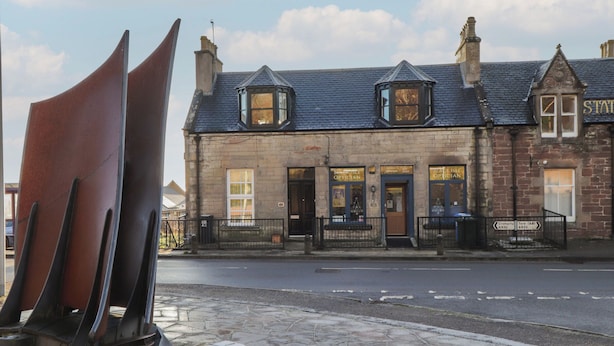 Un bâtiment en pierre à l’architecture traditionnelle, avec un pub appelé « Black Isle Optician » au rez-de-chaussée et une signalisation indiquant « Cromarty (A82) » sur le côté droit.