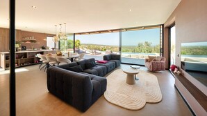 Uma sala de estar moderna com um sofá seccional, uma mesa de centro redonda e vista para o exterior.