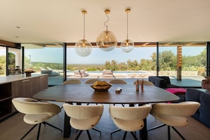 A modern dining area with a large table, six chairs, and a view of the outdoors. - Villa Maggio - Luxury modern villa with private pool  (Carovigno)