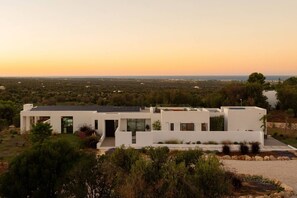 A modern white building with a flat roof, surrounded by greenery and a clear sky. - Villa Maggio - Luxury modern villa with private pool  (Carovigno)