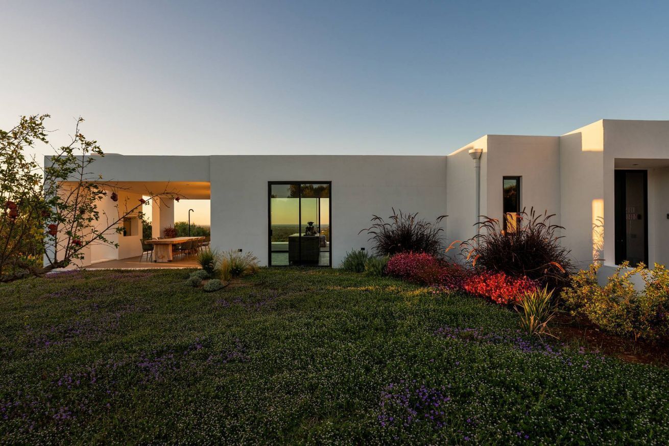 Une maison moderne dotée d’un patio, d’un coin repas et d’une grande porte vitrée.