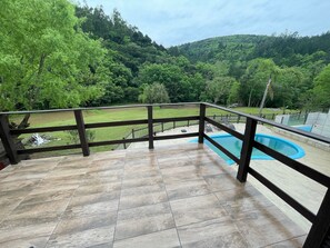A balcony with a view of a swimming pool and a grassy area.
