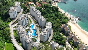 A high-rise hotel complex with a central swimming pool, surrounded by lush greenery and a beach. - Porto Real Resort - Leisure and Fun (Mangaratiba)