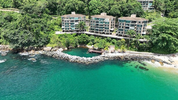 A coastal hotel with multiple buildings, a rocky shoreline, and clear turquoise water. - Porto Real Resort - Leisure and Fun (Mangaratiba)
