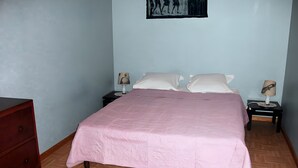 Une chambre à coucher comprenant un lit, deux tables de chevet avec des lampes, une commode et un tableau accroché au mur.