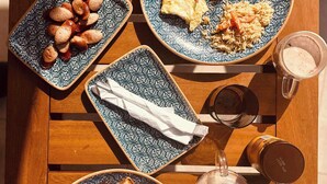 Una mesa de madera con platos de comida, vasos y una tetera.