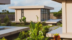 Un patio exterior moderno con techo plano, rodeado de vegetación y cerca de madera.