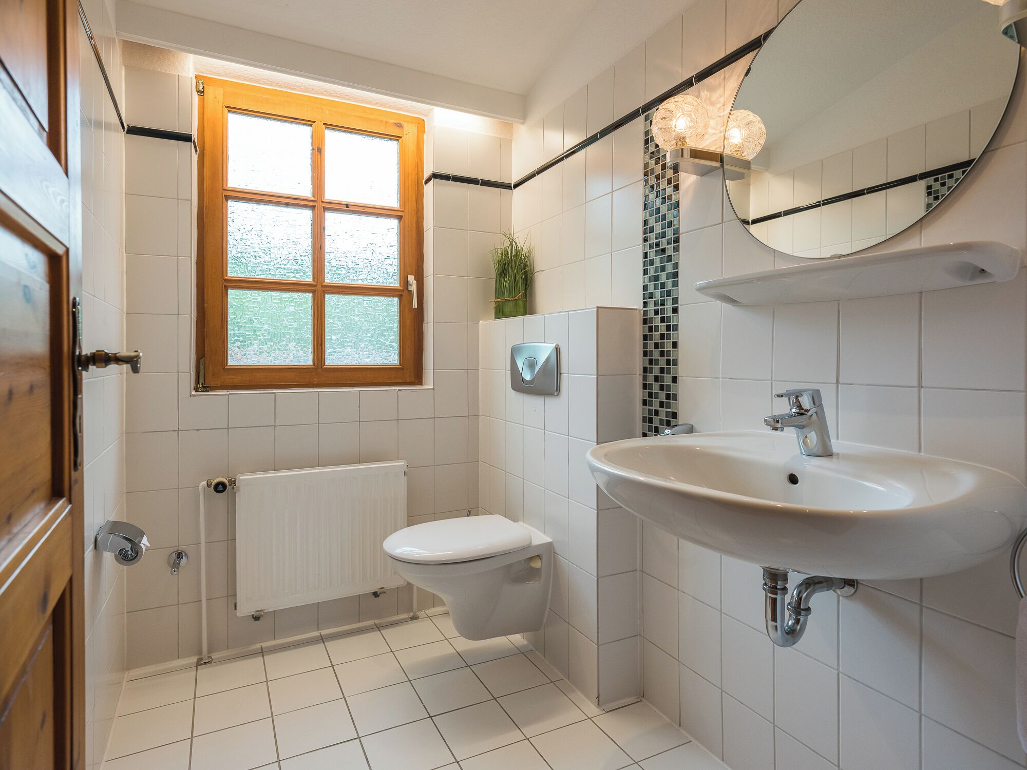 Ein modernes Badezimmer mit Toilette, Waschbecken und einem Fenster.