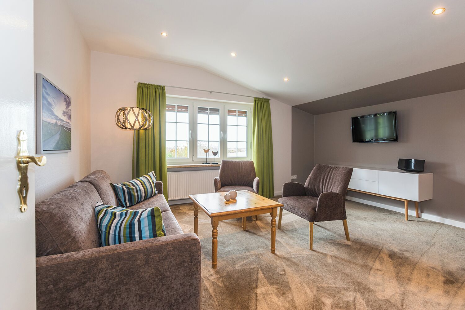 A modern living room with a sofa, armchairs, a coffee table, and a TV.