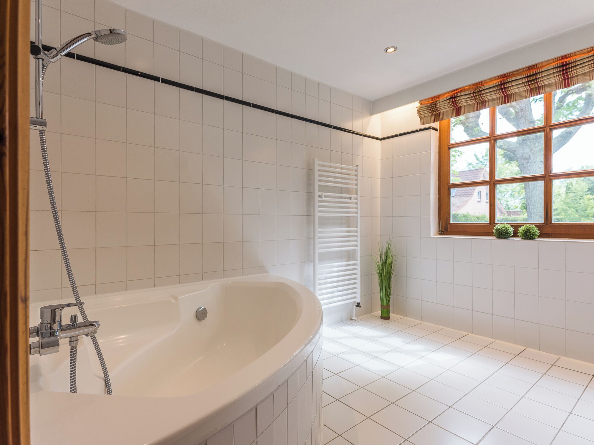 Un baño moderno con una bañera independiente, un ventanal con vistas a la vegetación y un perchero para toallas.