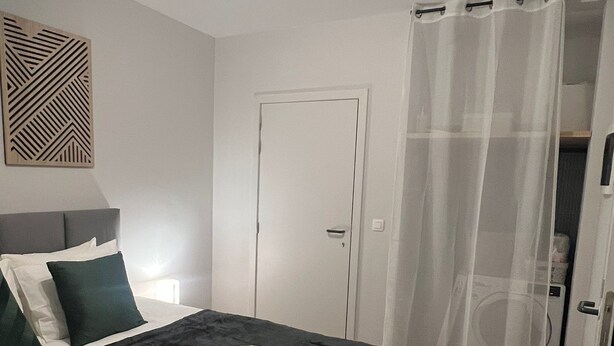 Un dormitorio con cama, una puerta y una cortina.