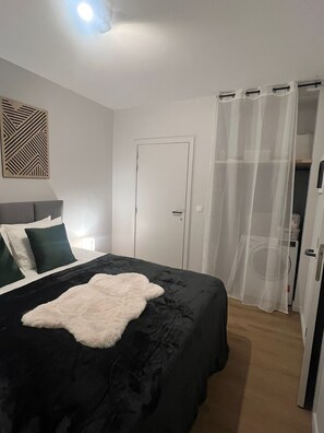 Een slaapkamer met een bed, een deur en een gordijn.
