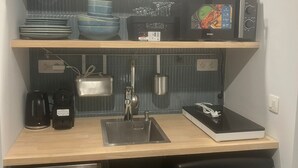 Cocina compacta con fregadero, cafetera, microondas y refrigerador pequeño.