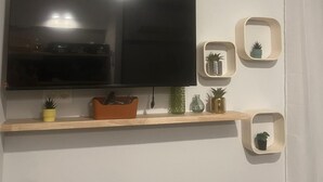 Un televisor de pantalla plana montado en la pared sobre una repisa de madera con adornos.
