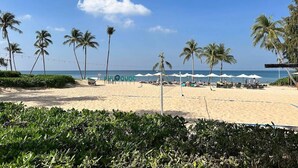 A beach with palm trees, umbrellas, and lounge chairs. - MK Hotel Phu Quoc (Phu Quoc)