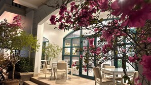 An indoor seating area with a table and chairs, surrounded by potted plants and blooming flowers. - MK Hotel Phu Quoc (Phu Quoc)