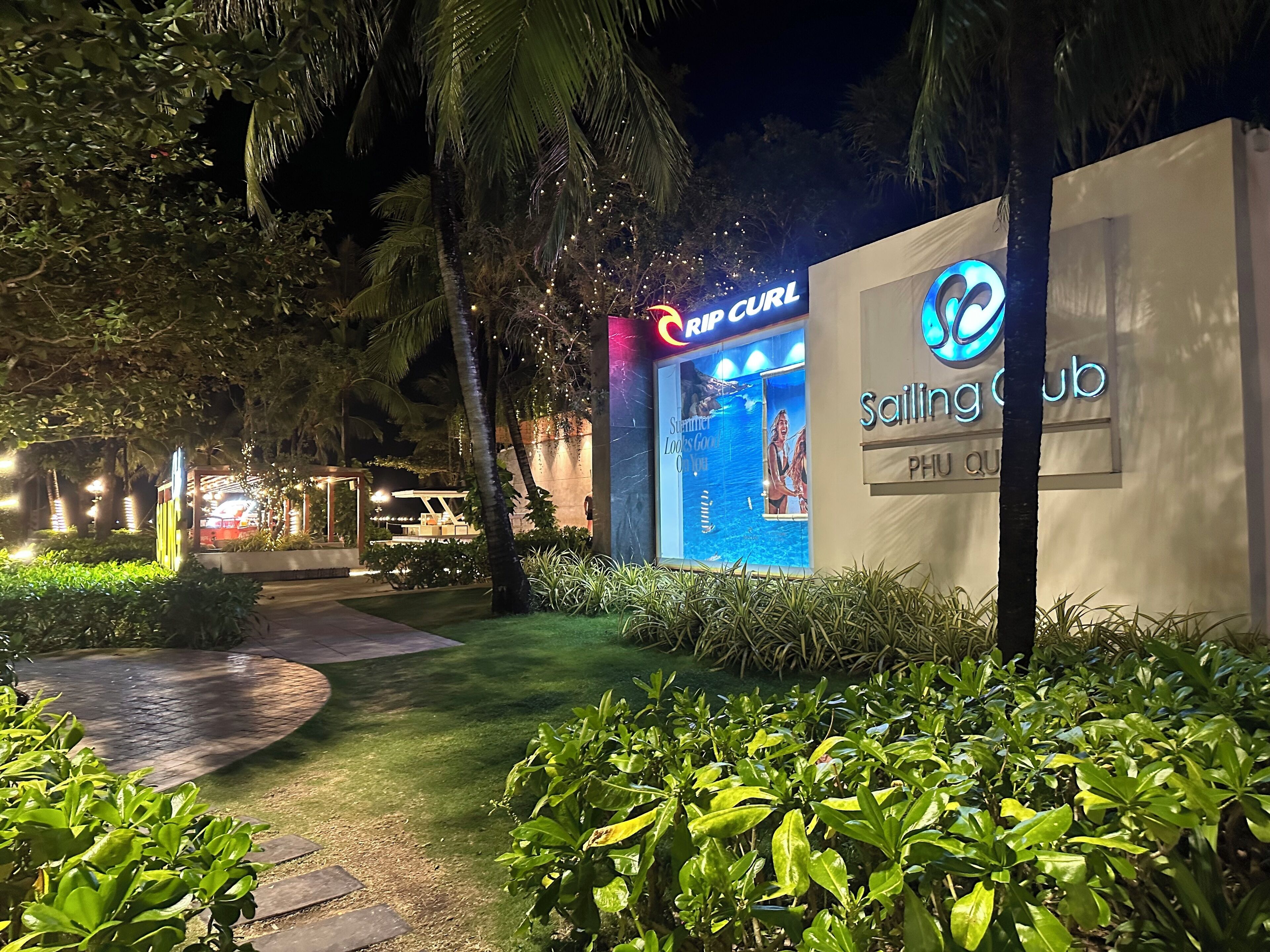 A well-lit outdoor area with a sign for 'Rip Curl' and 'Sailing Club' indicating a sports facility.