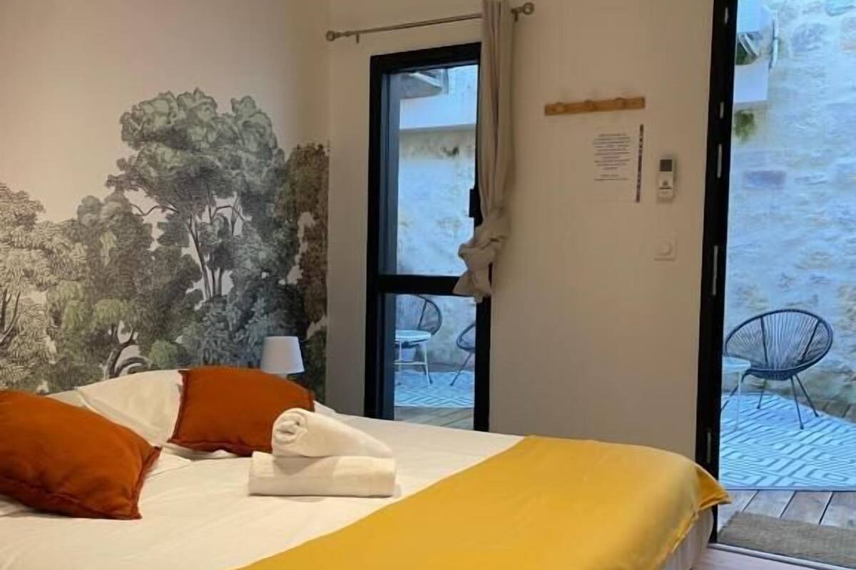 Un dormitorio con una cama, un edredón amarillo y un mural de árboles en la pared.