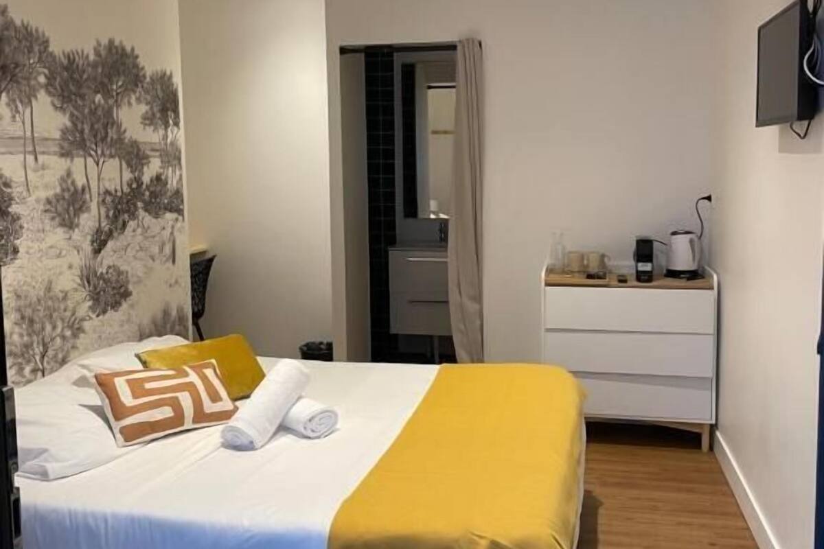 Un dormitorio moderno con una cama, mesita de noche y televisor montado en la pared.