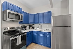 Una cocina moderna con armarios azules, electrodomésticos de acero inoxidable y piso de madera.