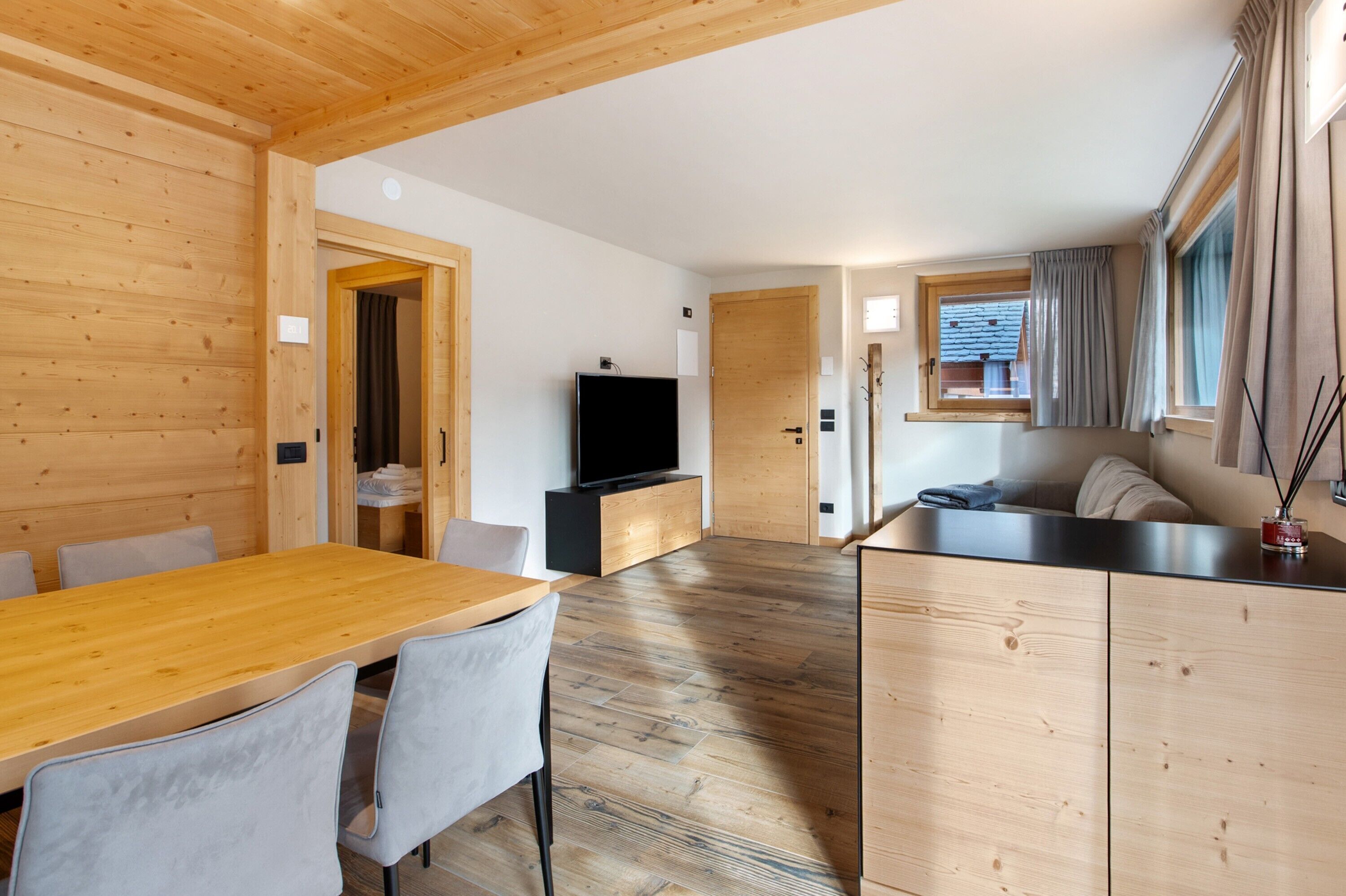 Ein Holzinterieur mit Esstisch, Stühlen, Fernseher und einer Couch.