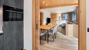 Una cocina moderna con horno empotrado y comedor con mesa y sillas de madera.
