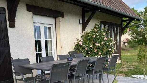 An outdoor patio with a table and chairs, surrounded by a garden with a white gravel border and a large plant in the foreground. - Oh Fleurs des Champs (Chaumont-sur-Tharonne)