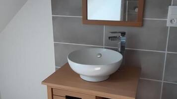 Une salle de bain avec un lavabo blanc, un meuble-lavabo en bois et un miroir au mur.