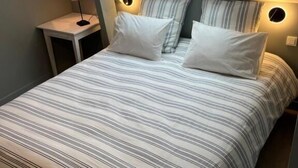 A bedroom with a skylight, a bed with striped bedding, bedside lamps, and a small table. - Oh Fleurs des Champs (Chaumont-sur-Tharonne)