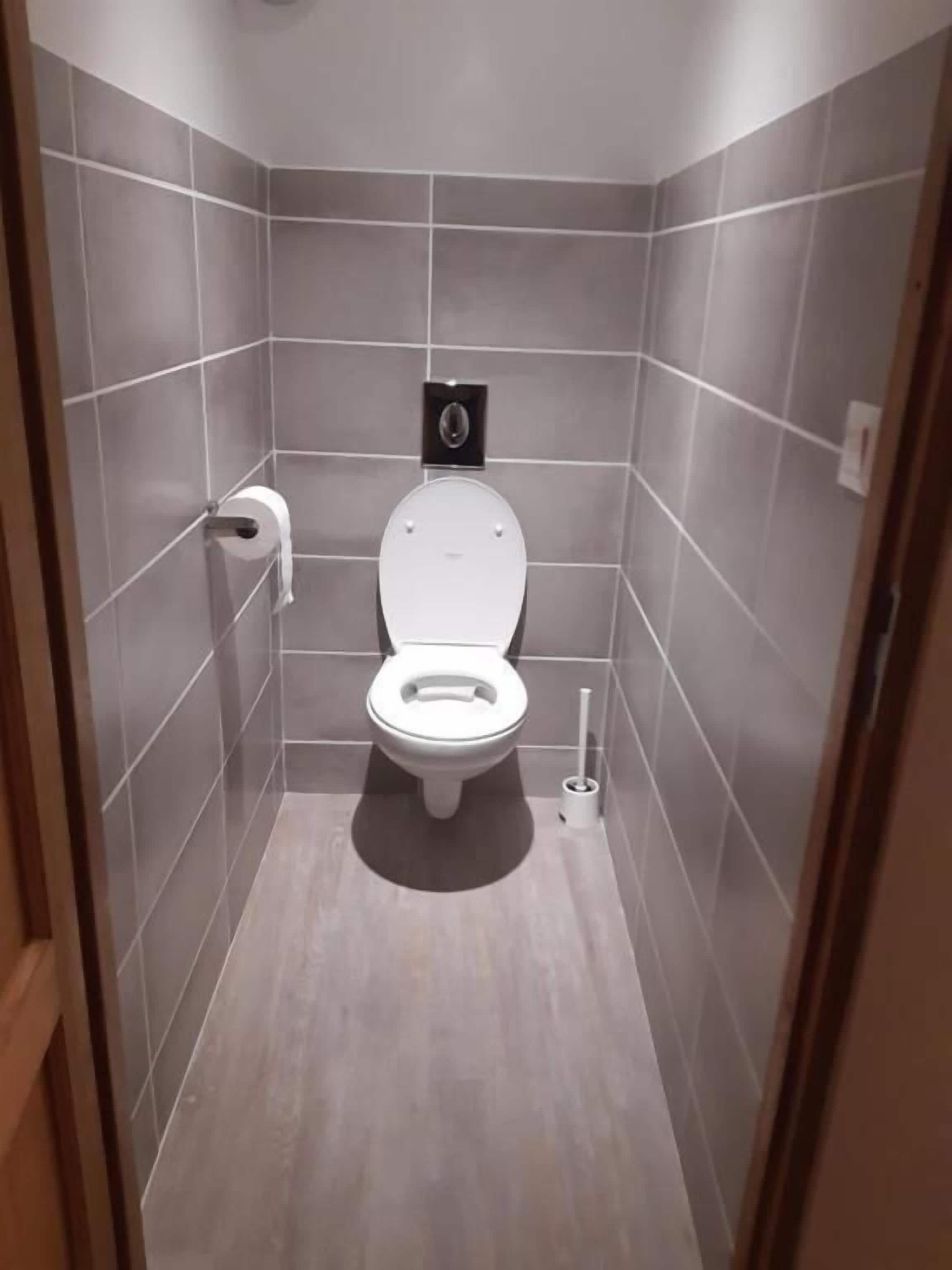 A small, modern bathroom with a toilet, a toilet paper holder, and a bidet.