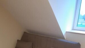 A single brown sofa in a room with wooden flooring and a sloped ceiling. - Oh Fleurs des Champs (Chaumont-sur-Tharonne)