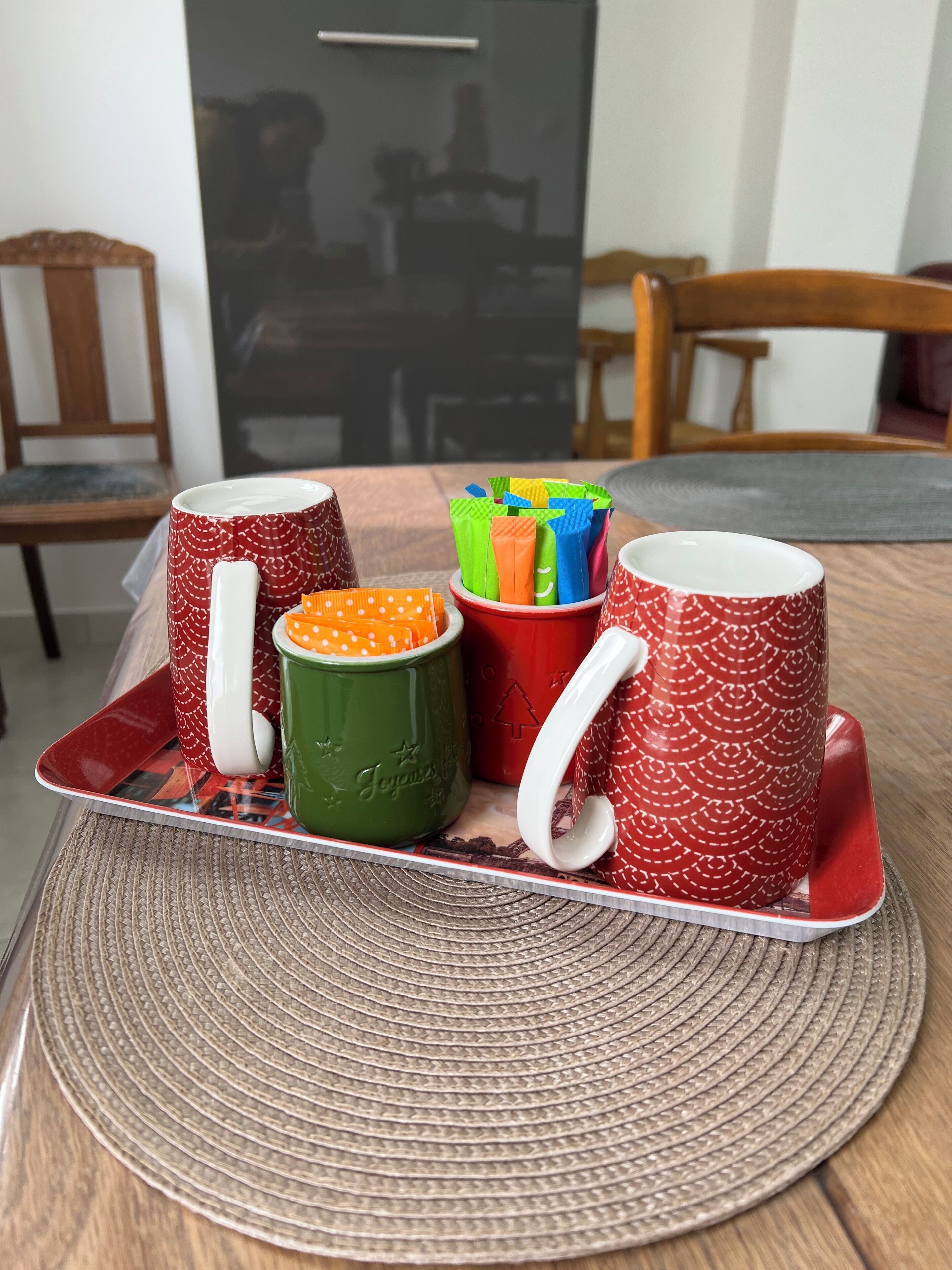 Un plateau avec quatre tasses et un ensemble de pailles colorées, le tout posé sur un set de table en fibres tressées.