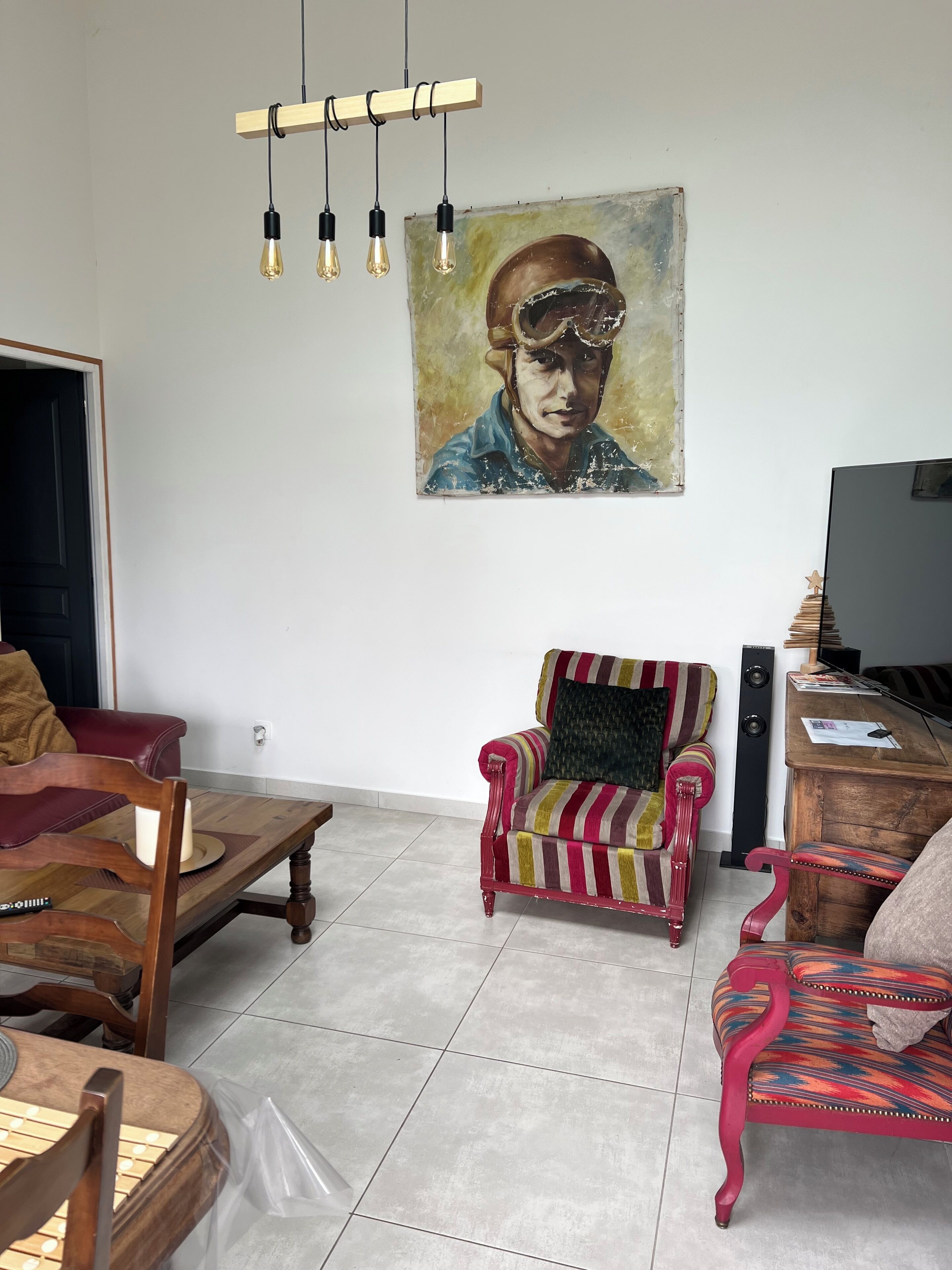 Een woonkamer met een gestreept fauteuil, een houten salontafel, een televisie en een schilderij aan de muur.