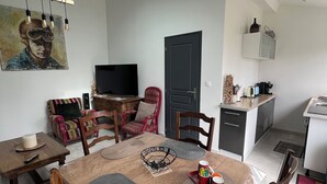 A dining area with a table, chairs, and a TV in the background. - Adrien's place! (Châlette-sur-Loing)
