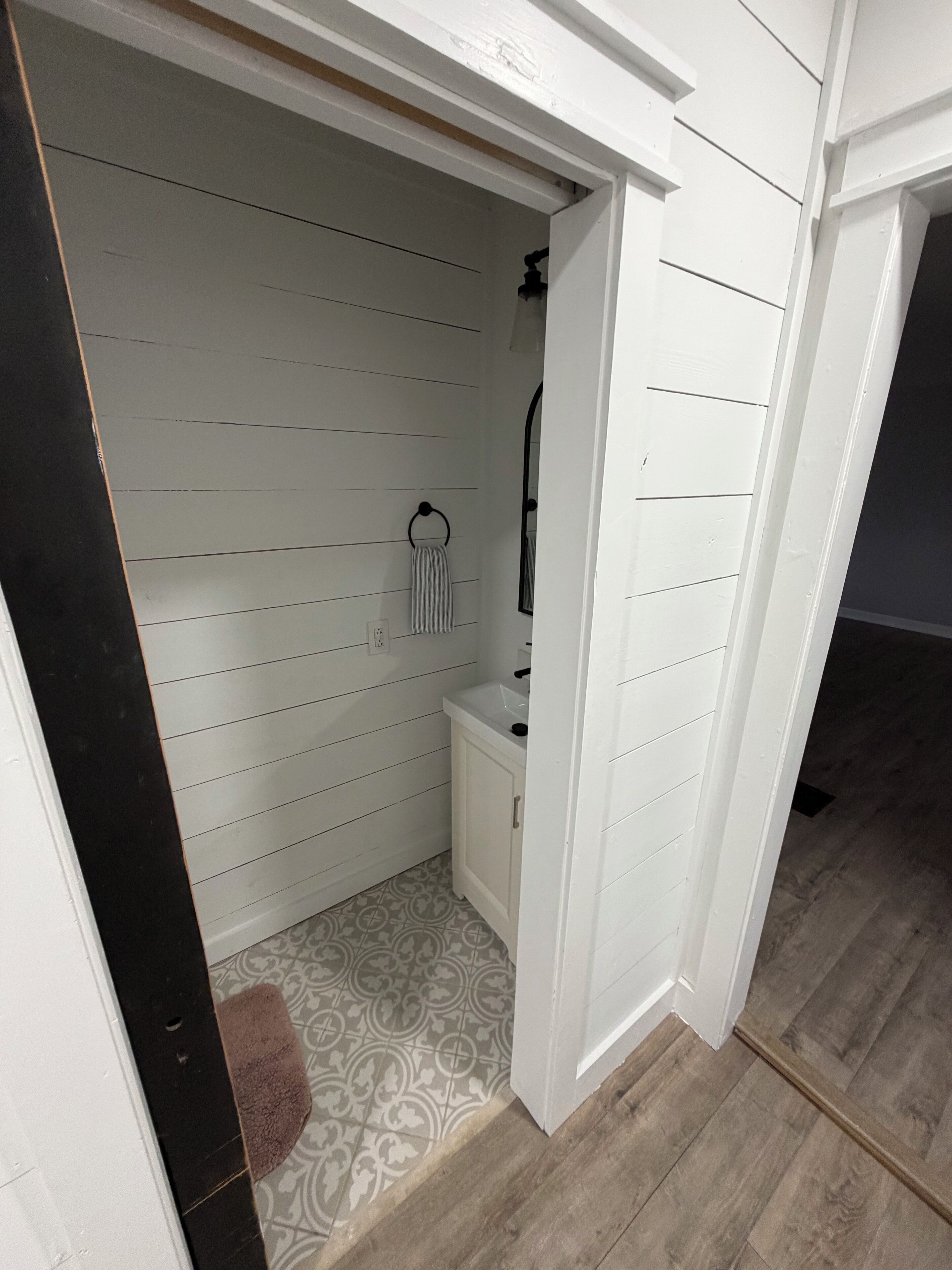 Een kleine badkamer met witte wanden, een enkele wastafel en een handdoekhouder.