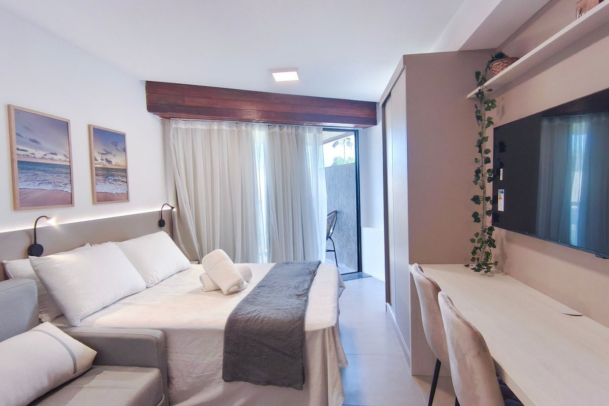 A hotel room with a bed, a sofa, a desk, a TV, and a window with curtains.