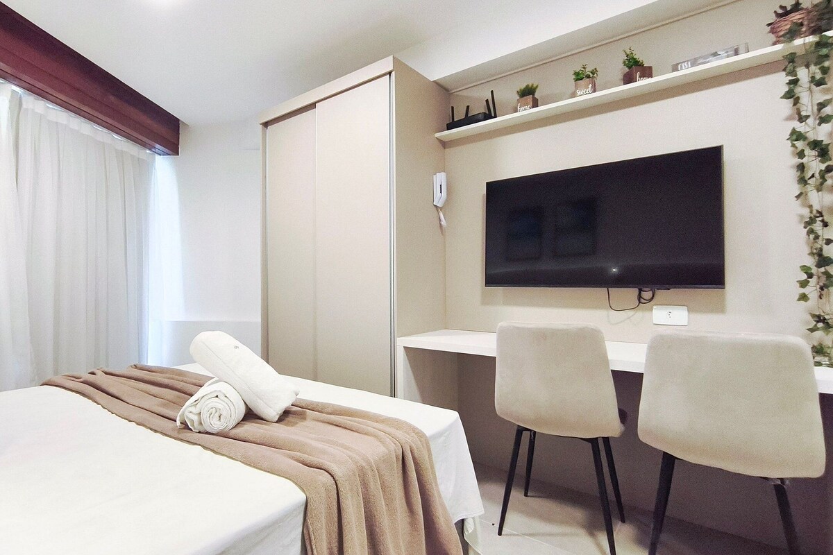 A hotel room with a bed, a desk, a chair, a television, and a wardrobe.