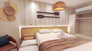 A modern hotel room with a wooden headboard, a bed with white linens, a brown throw blanket, and a unique wall decoration of two paddles. - Flats no Carneiros Atlantico - Proximo da Igrejinha (Tamandaré)