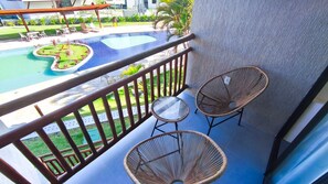 Un balcon avec une piscine, deux fauteuils en osier et une table.