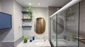 Ein modernes Badezimmer mit zwei Waschbecken, einem Spiegel mit Holzschublade und einer Duschkabine.