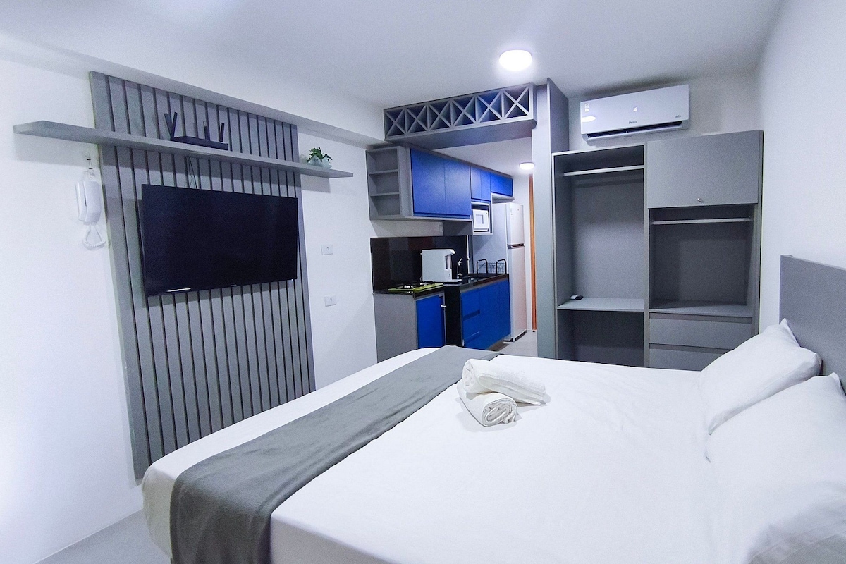 Ein Hotelzimmer mit Bett, Fernseher, Küchenzeile und Kleiderschrank.