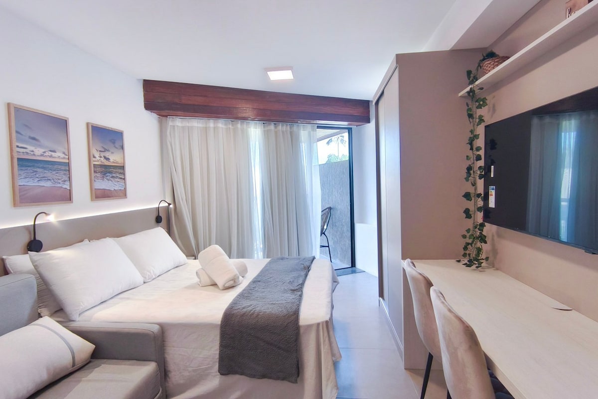 Ein Hotelzimmer mit Bett, einer Couch, einem Schreibtisch, einem Fernseher und einem Fenster mit Vorhängen.