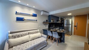Un espace de vie compact comprenant un canapé, une table à manger, des chaises et un coin cuisine.