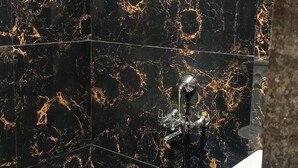 A bathroom with black marble walls and a white sink. - Shree ShyamRaj Hotel (Ujjain)